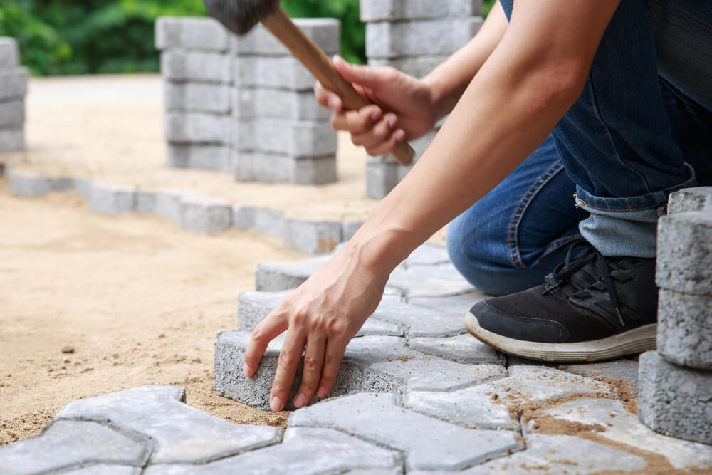 Hand of Professional Paver Worker Lays Paving Stones in Layers for Pathway, Labor and Industry Concept.