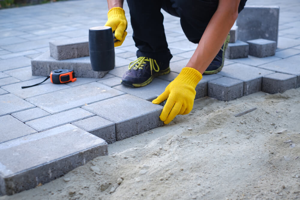 The Master in Yellow Gloves Lays Paving Stones in Layers.