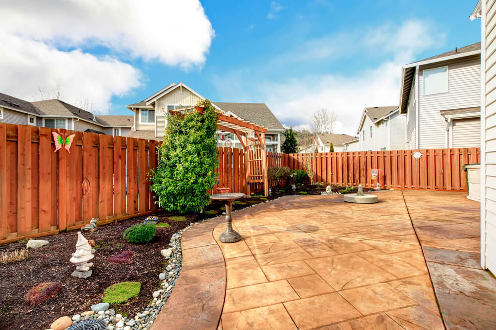 Fenced Backyard With Concrete Tile Floor Deck and Decorated Flower Bed
