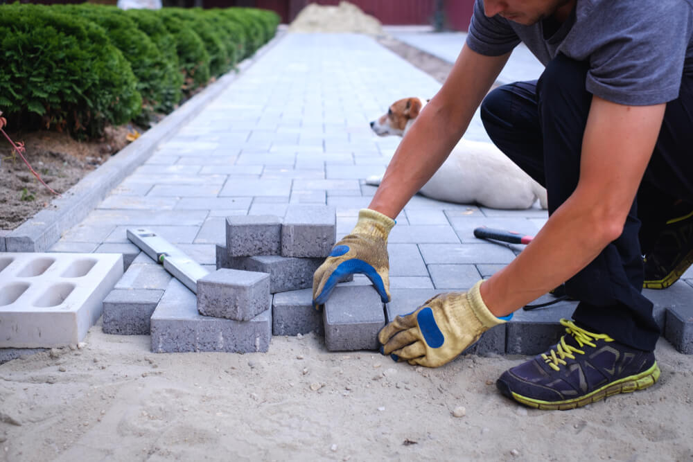 The Master in Yellow Gloves Lays Paving Stones in Layers. 