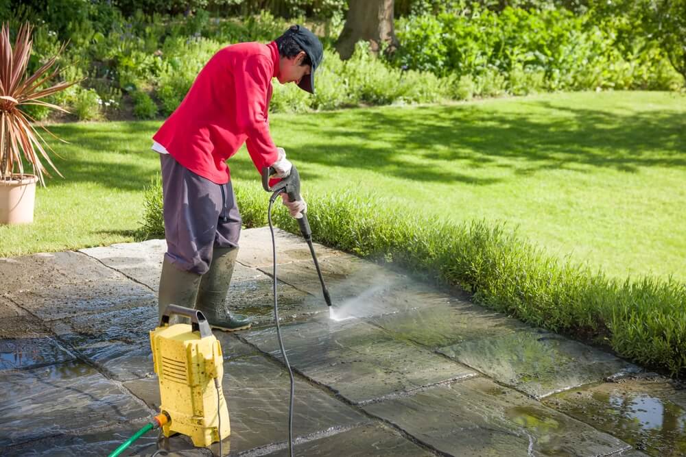 Jet Washing a Patio. Woman High-Pressure Washing, Power Washing, or Cleaning a Garden Terrace.