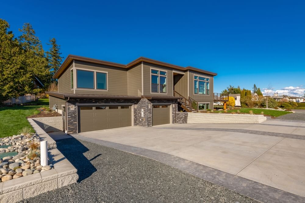 Contemporary Home Exterior With Dark Blue Sky Stamped Concrete Driveway Brown House And Expansive Deck