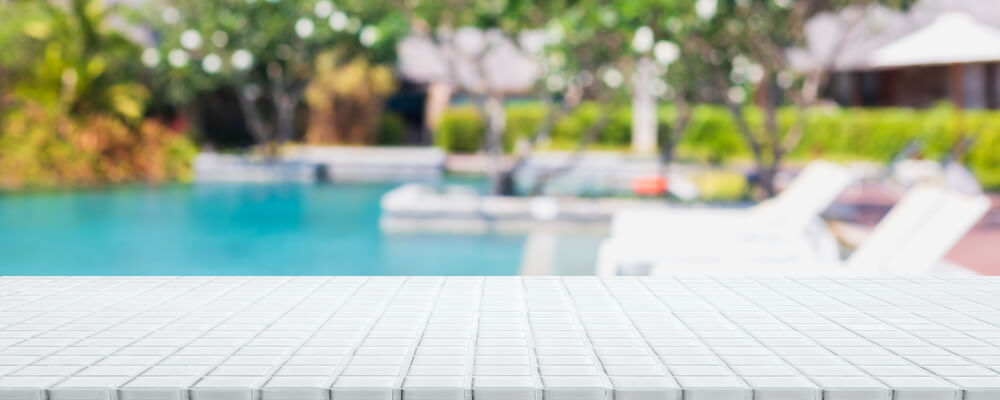 Empty White Ceramic Mosaic Table Top And Blurred Swimming Pool In Tropical Resort