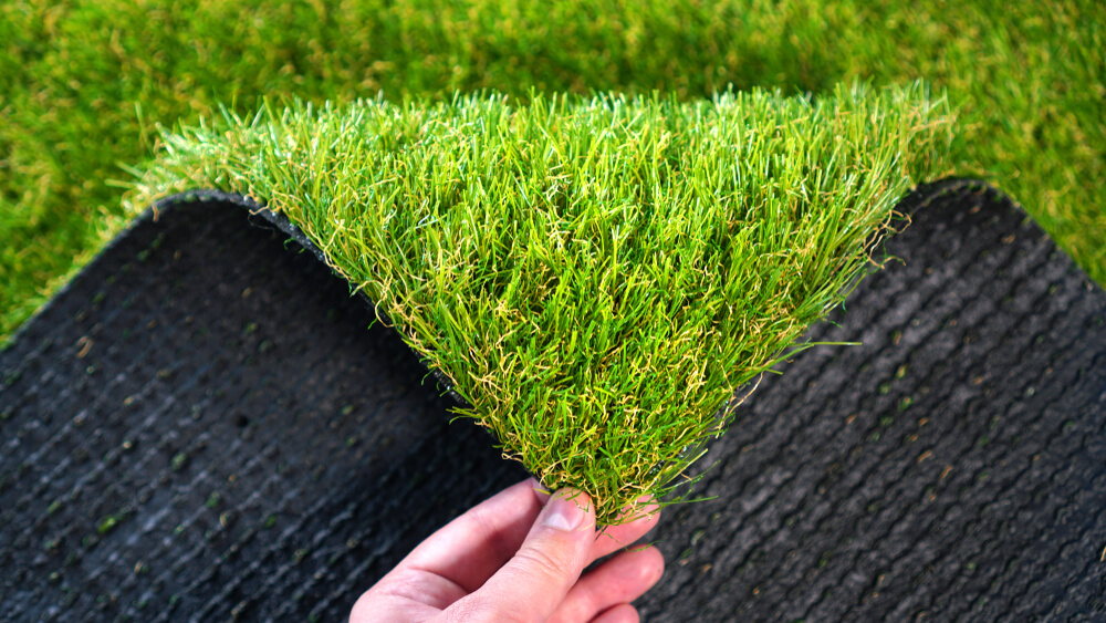 Hand Holding An Artificial Grass Roll Greenering With An Artificial Turf