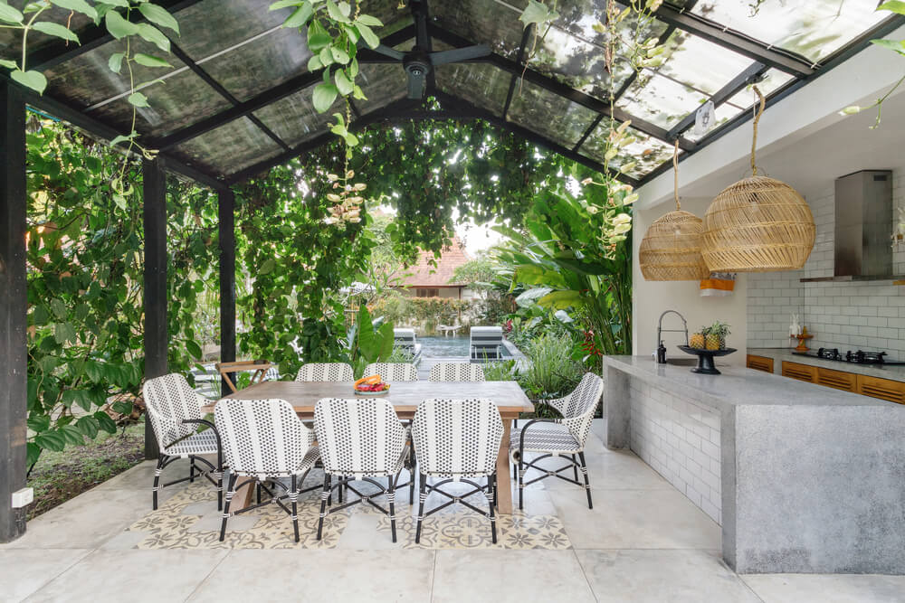Open Kitchen With Empty Dining Room Table And Chairs Outside Against Green Fresh Plants On Background