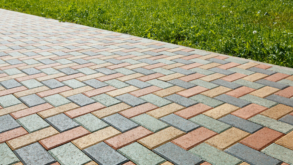 Colorful Cobblestone Road Pavement And Lawn Divided By A Concrete Curb